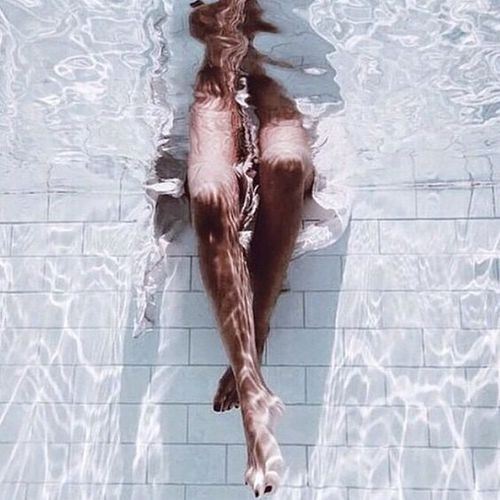 プールの中に脚を入れる女性の画像