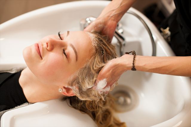 アミノ酸シャンプーで美容師に洗髪される女性の画像