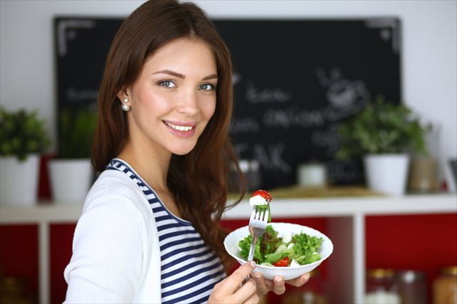 栄養たっぷりのサラダを食べる女性の画像