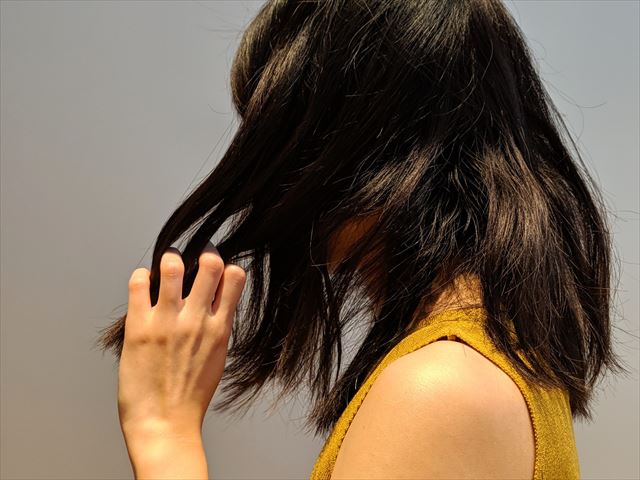 ボサボサの髪をさわる女性の画像